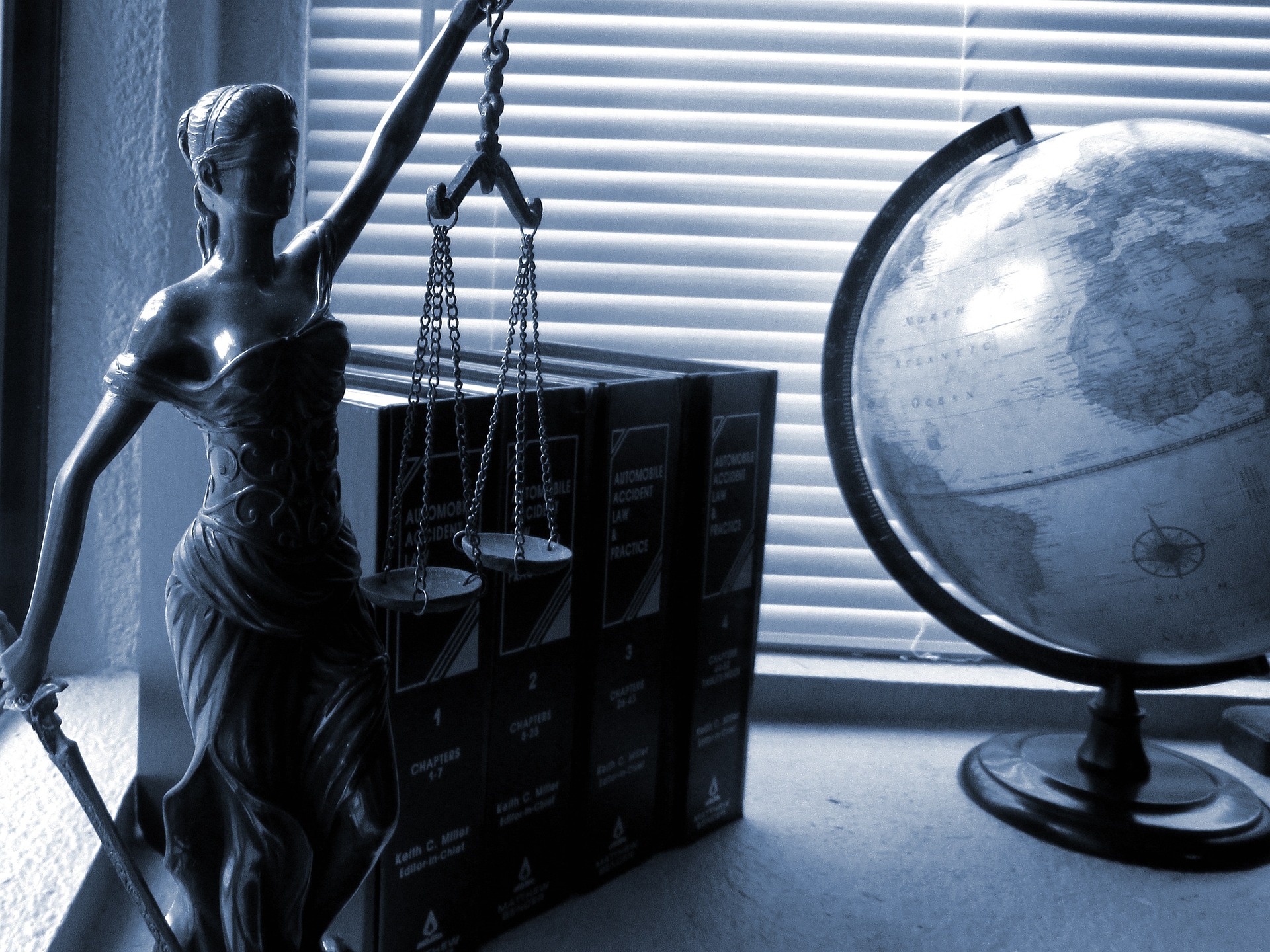 The scales of justice next to some books and a globe