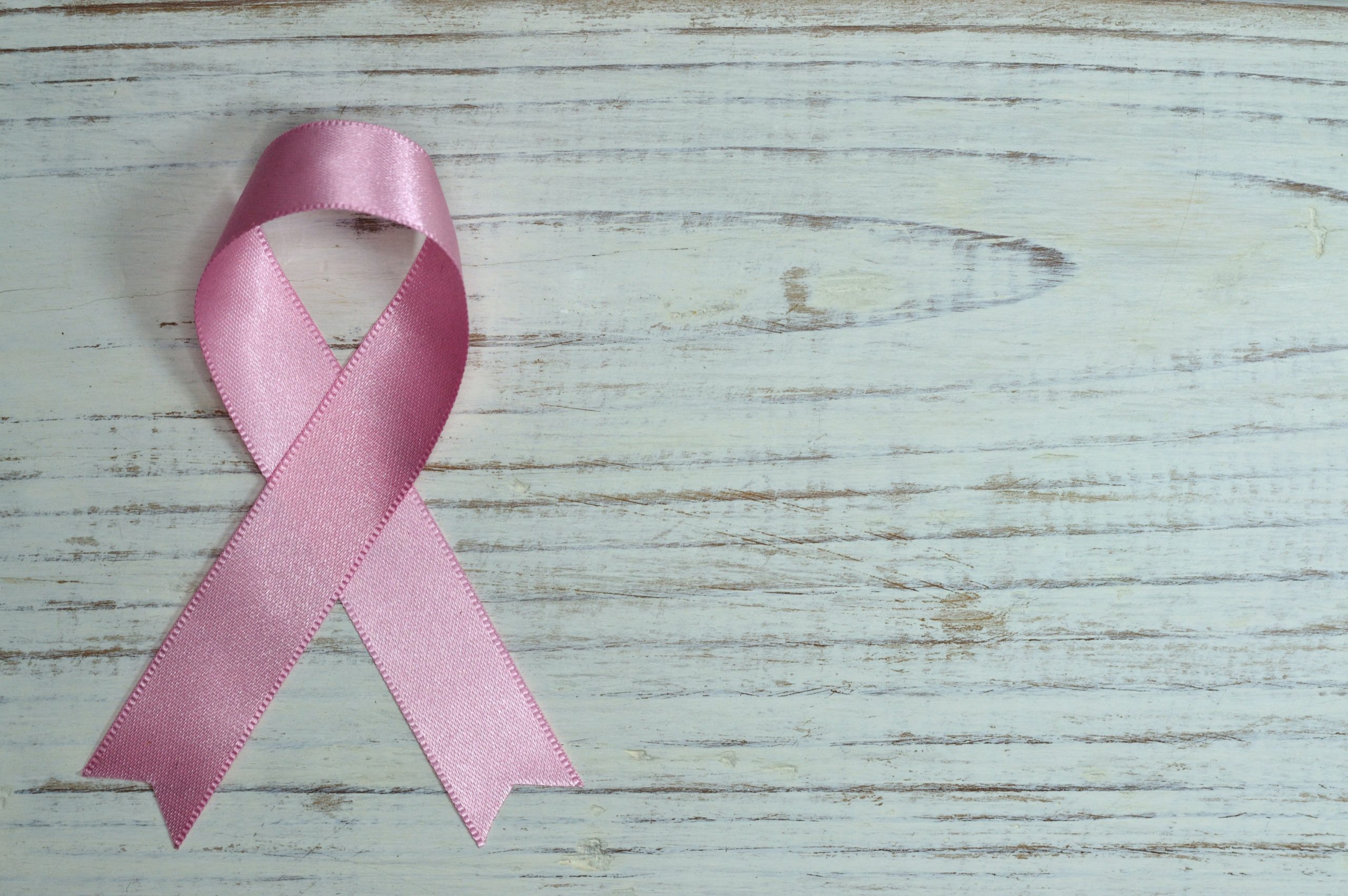 Pink breast cancer ribbon on a wooden table